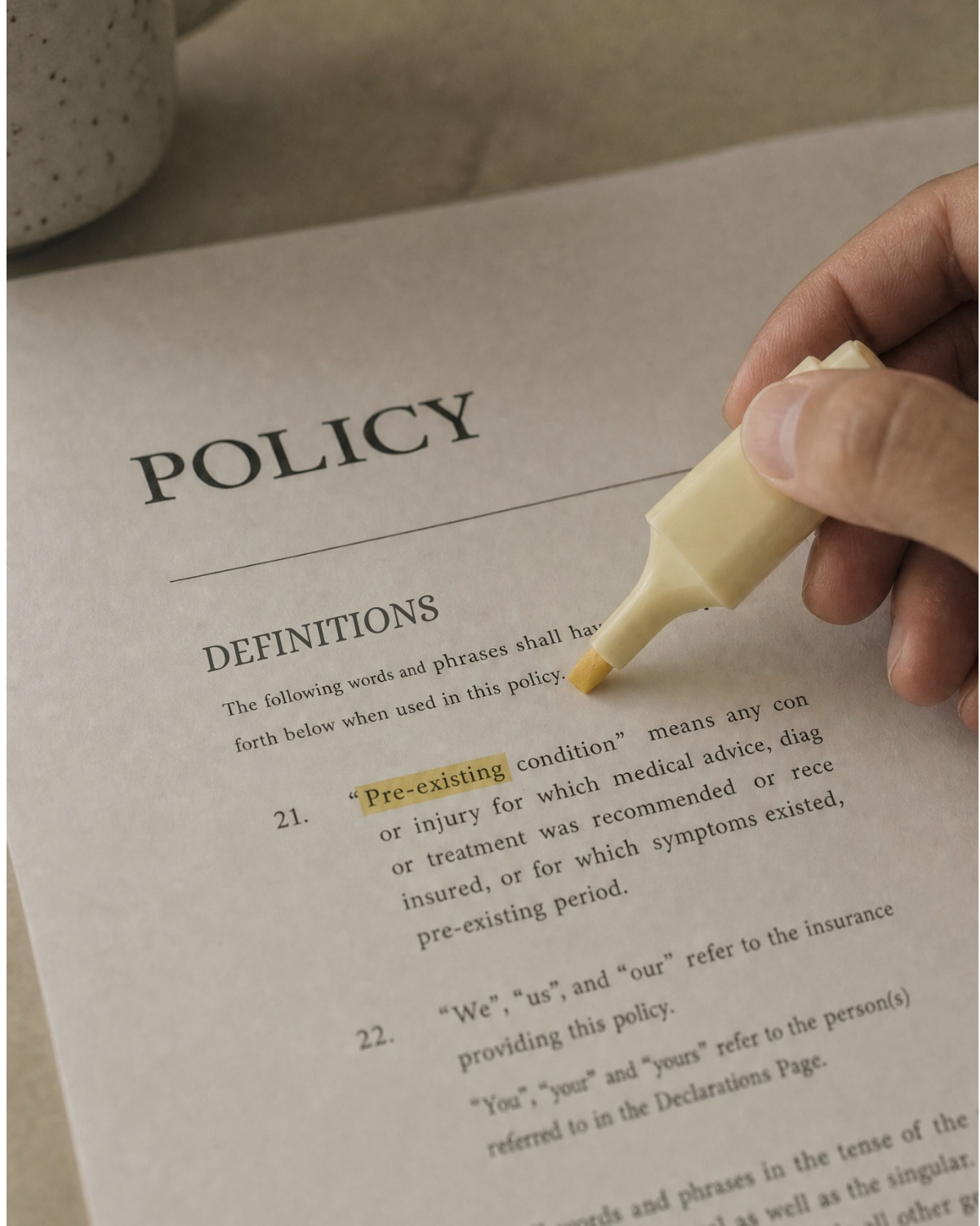 Hand highlighting the pre-existing conditions clause on a pet insurance policy page